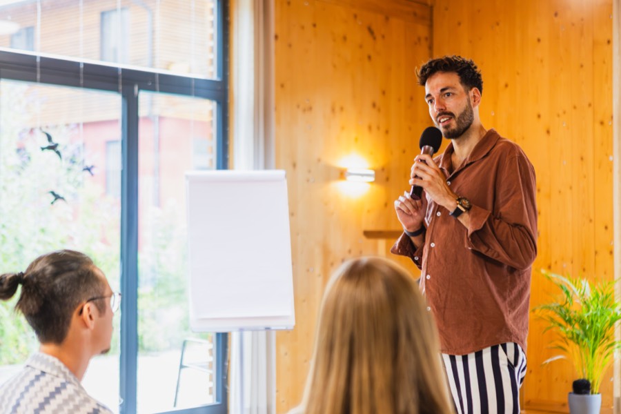 Speaker mit Mikrofon vor der Gruppe