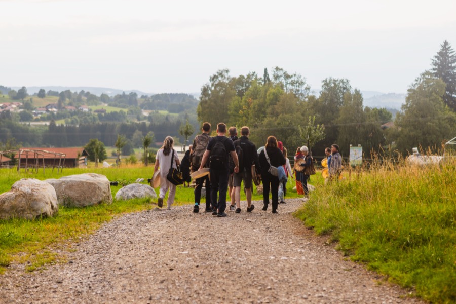 Die Gruppe geht mit Trommeln über einen Feldweg in den Voralpen